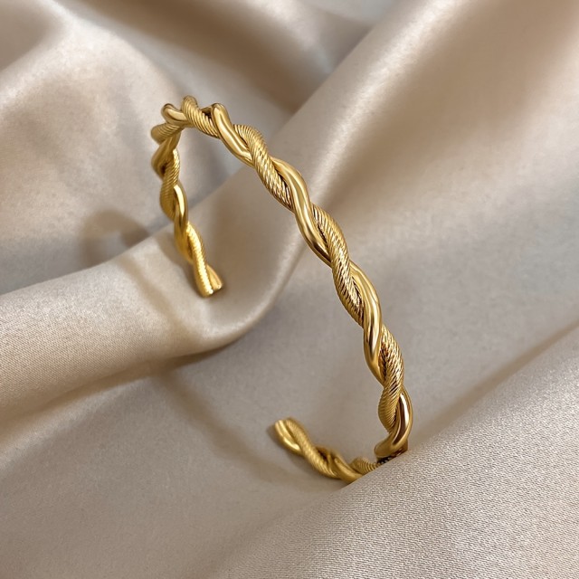Odprta zlata zapestnica z elegatnim zvitim dizajnom