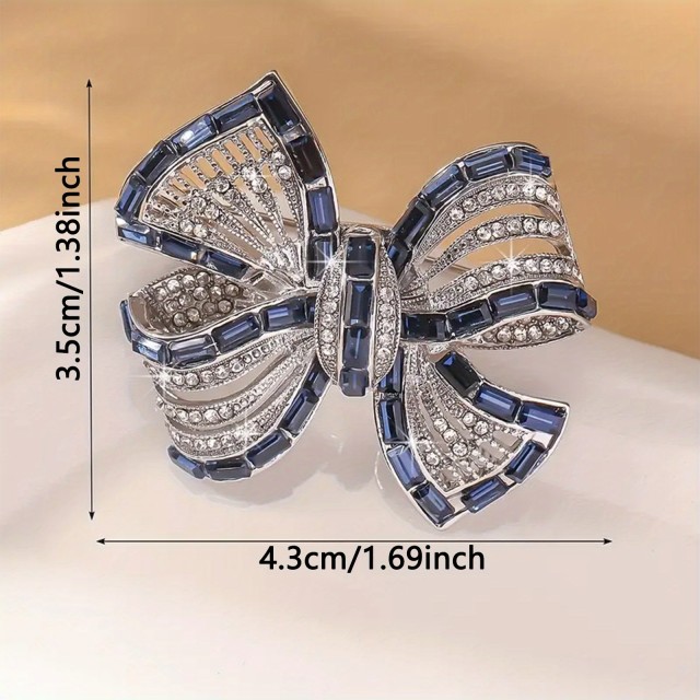 Ženska broška z okrasnimi kamni v obliki pentlje