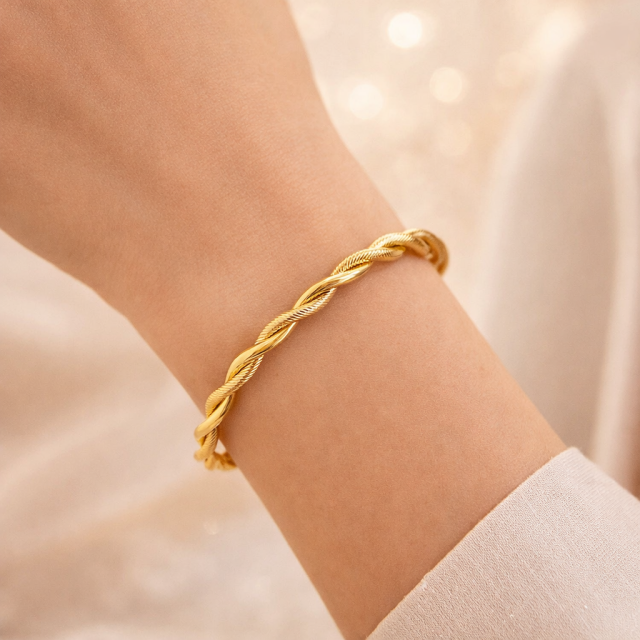 Odprta zlata zapestnica z elegatnim zvitim dizajnom